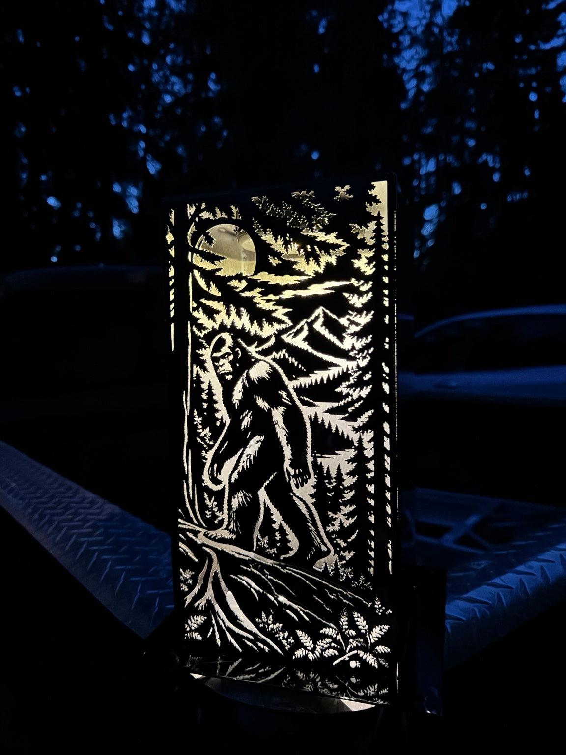 J Fab 6 by 12 inch Bigfoot luminary illuminated at night, with forest, mountains and moon cutouts