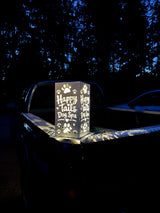 J Fab 6 by 12 inch Happy Tails Dog Spa luminary illuminated at night, showing two decorated faces